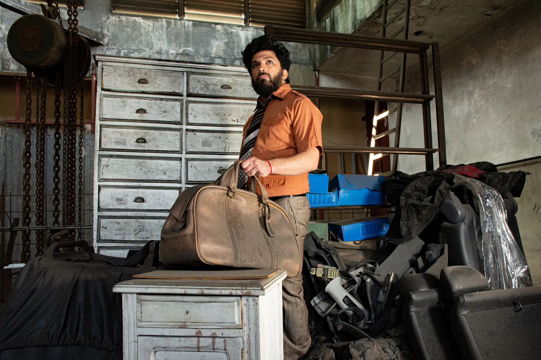 Gabriel Paez, agarrando un viejo bolso de cuero en un galpón desordenado