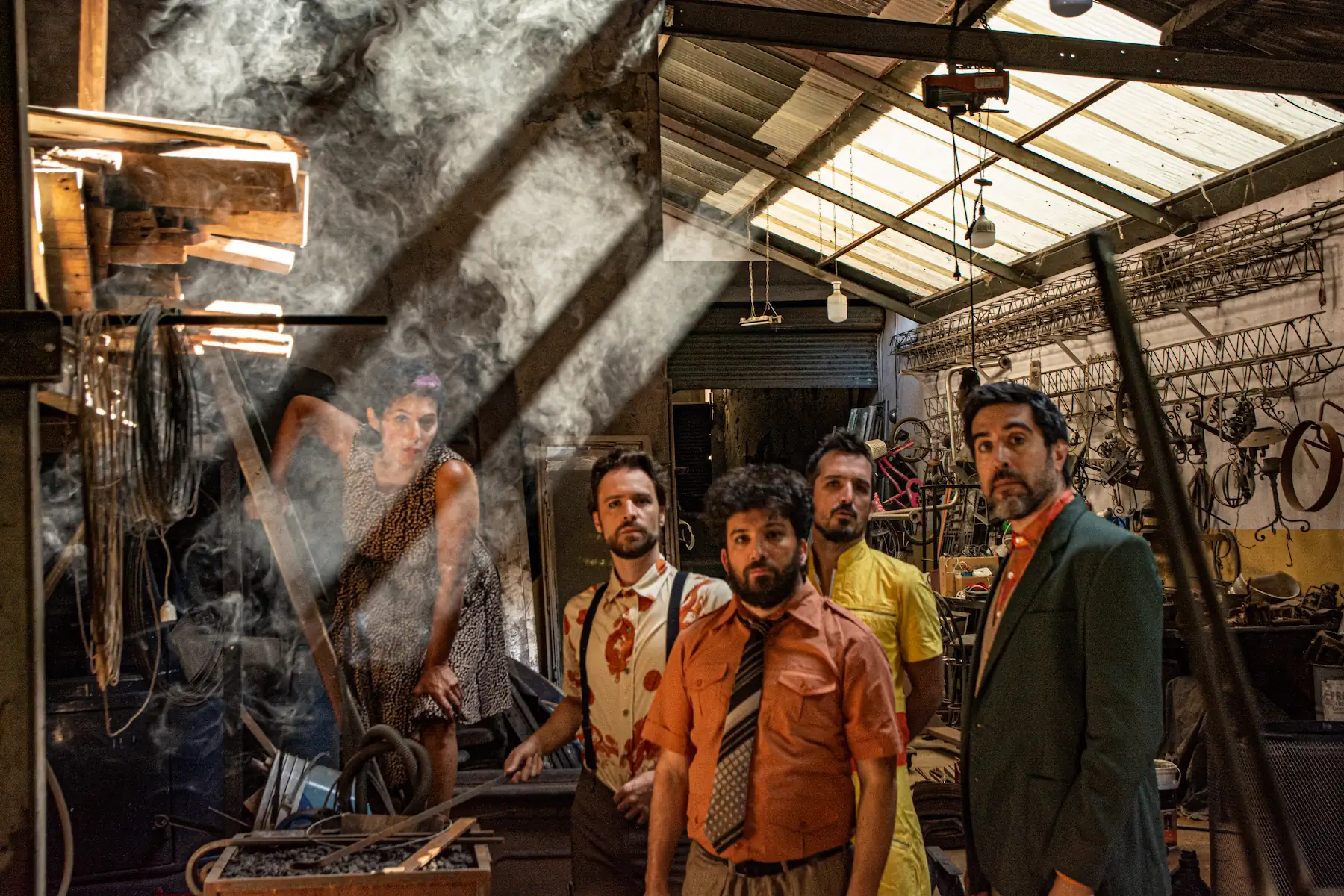 elenco de la bomba de humo, posa en un galpón herrería, con una capa de humo que los rodea