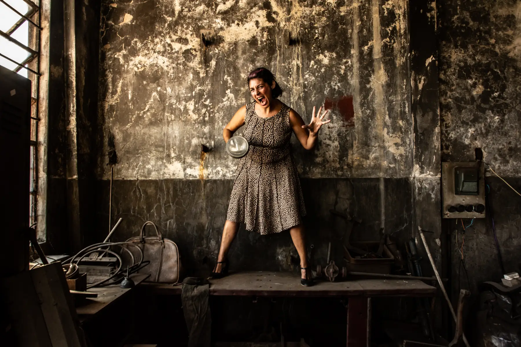 Eleonora Valdez integrante del grupo la bomba de humo impro, en un taller abandonado, gritando mientras sostiene un foco de iluminación