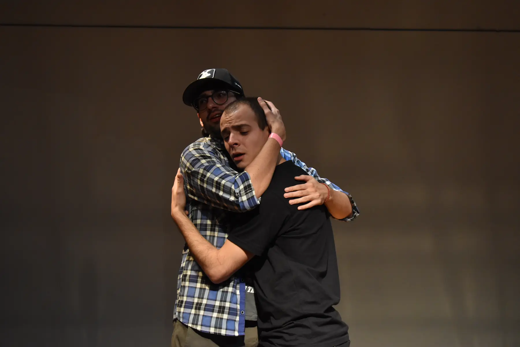 dos hombres abrazándose en escena/ two men embracing on stage