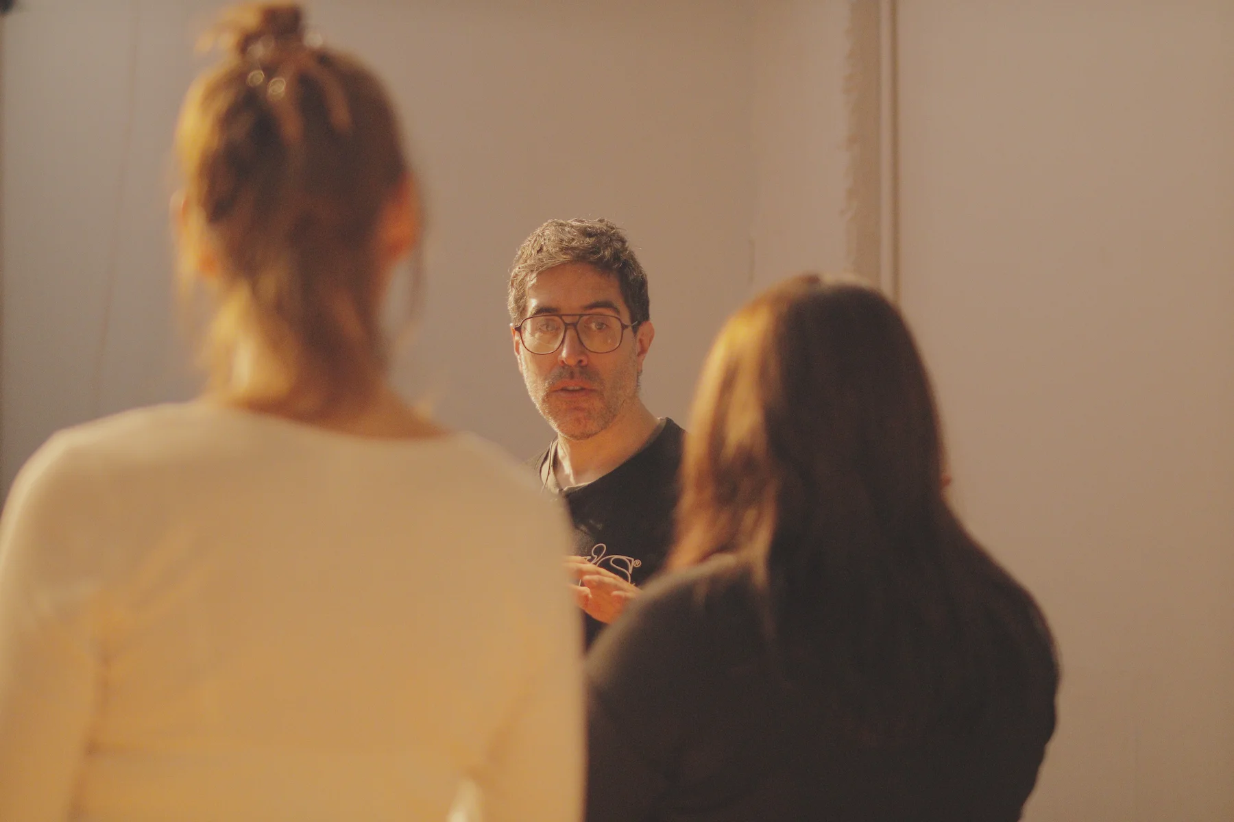 Charly Arzulian dando un entrenamiento de improvisación, hablando con dos participantes vistos de espaldas