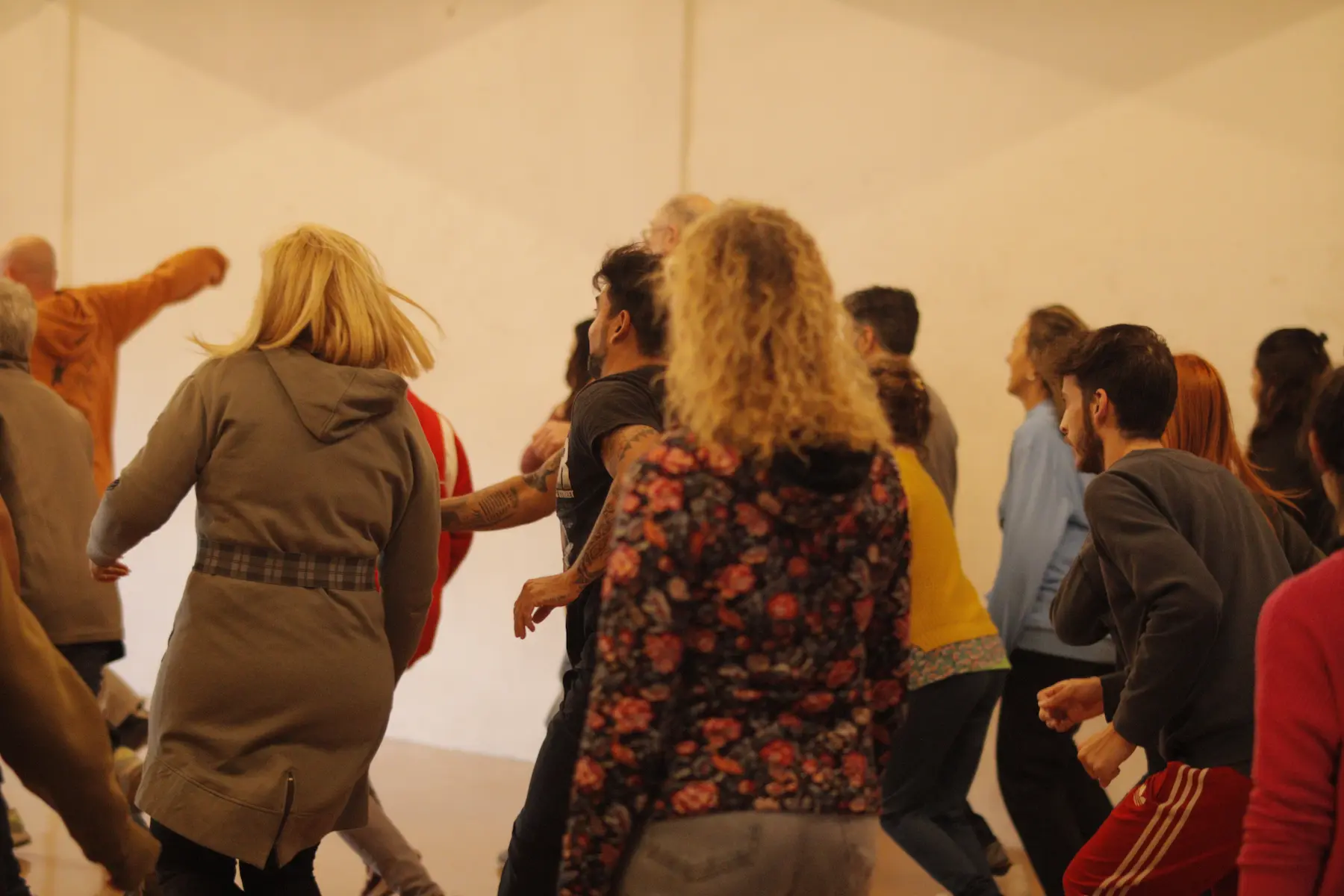 Grupo de personas realizando un calentamiento improvisado en un taller
