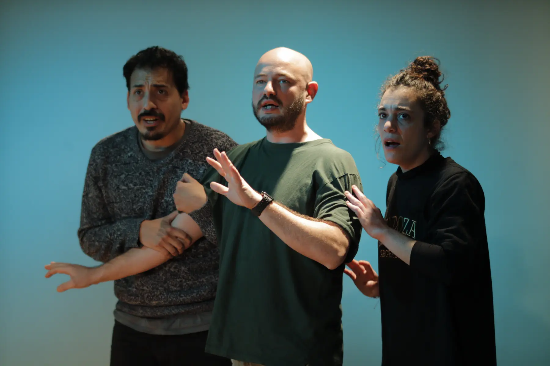 Tres actores en una actuaci贸n de improvisaci贸n, expresando sorpresa y tensi贸n