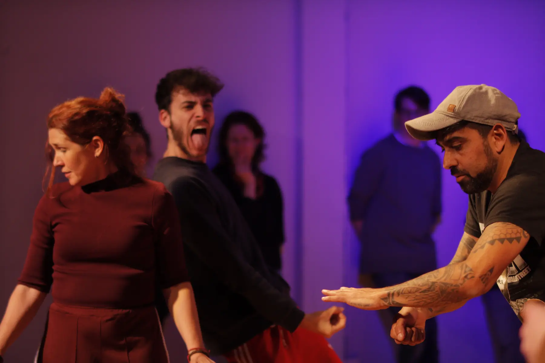 Escena de improvisaci贸n teatral con tres actores: una mujer, un hombre con expresi贸n c贸mica con la lengua fuera y otro concentrado con los brazos extendidos