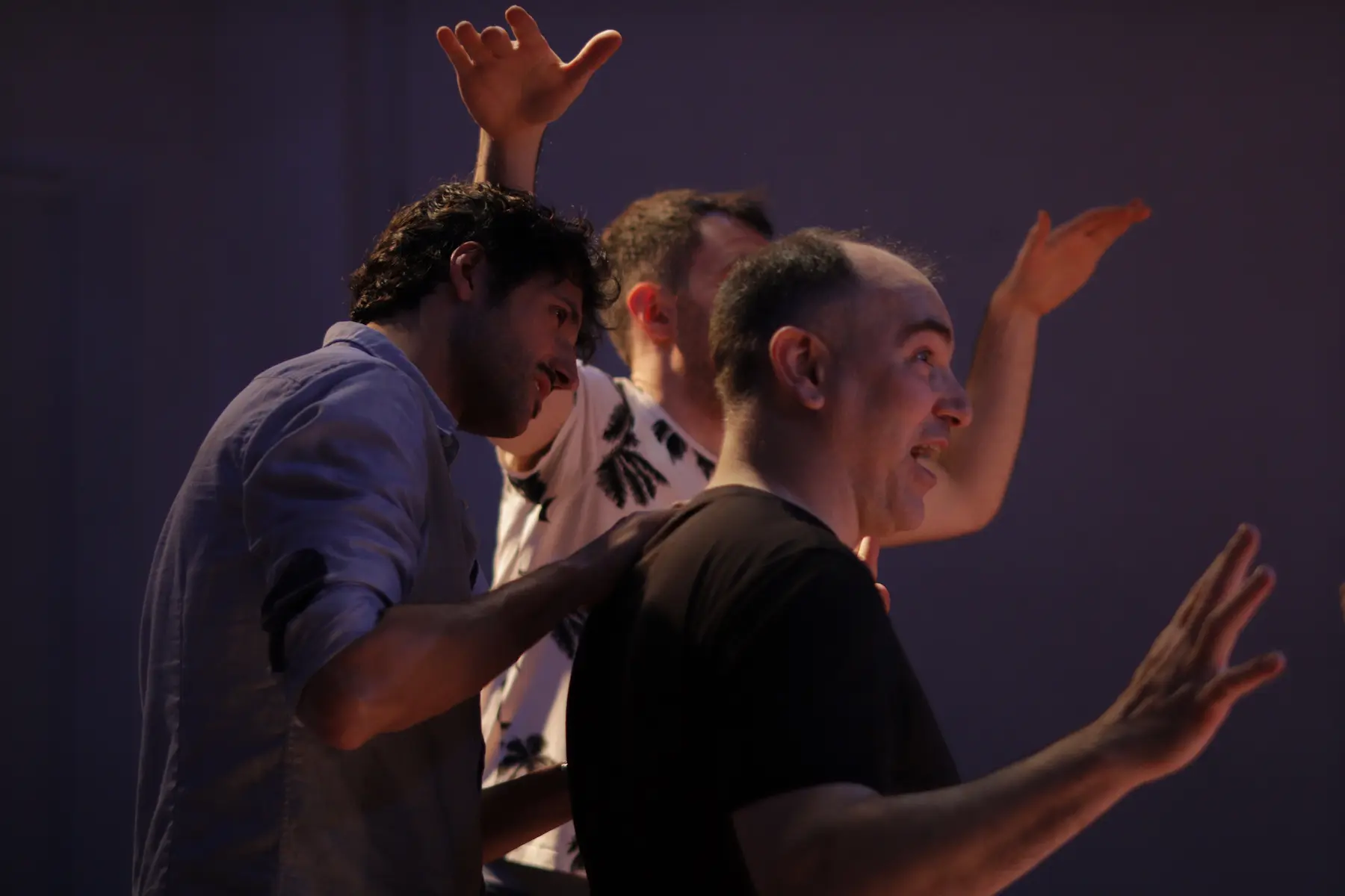 Tres hombres de pie, con las manos en alto, capturando un instante divertido y espontáneo.