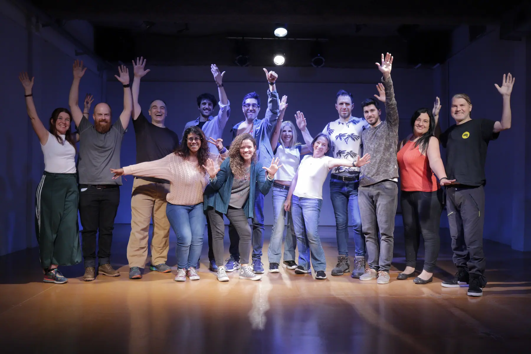 Grupo de improvisadores posando juntos en el escenario con los brazos levantados y sonriendo