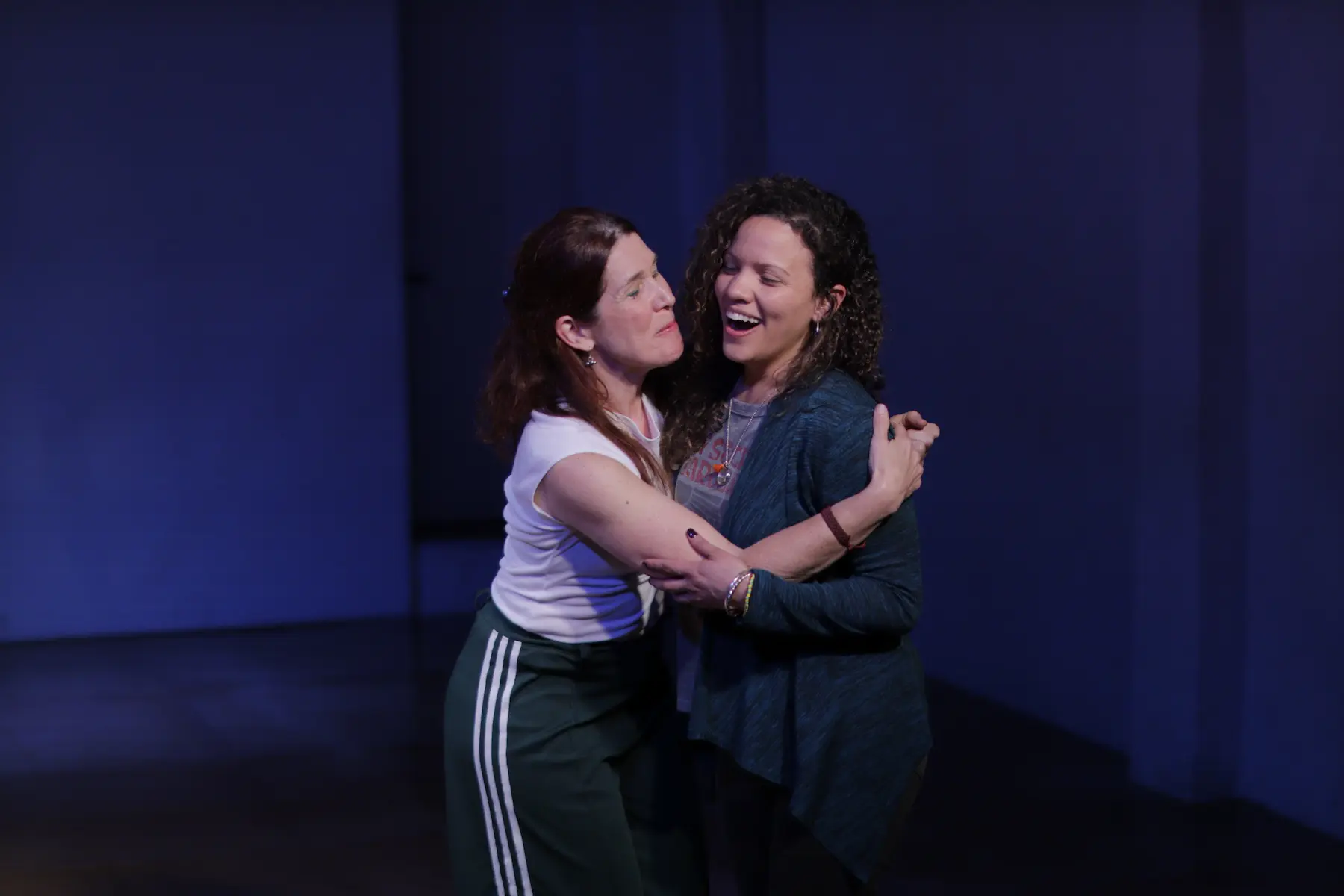 Dos mujeres abrazándose y sonriendo en una escena de improvisación
