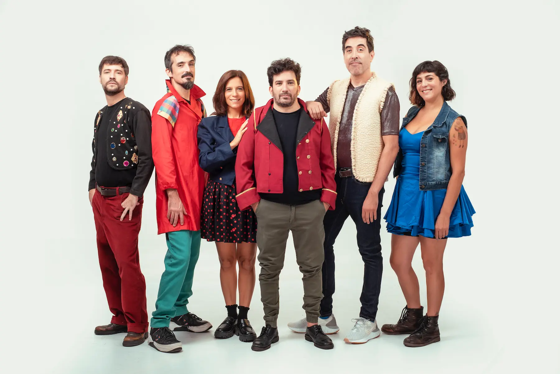 Elenco de "La Bomba de Humo Impro" posando con vestuario teatral colorido y expresiones lúdicas sobre fondo claro.